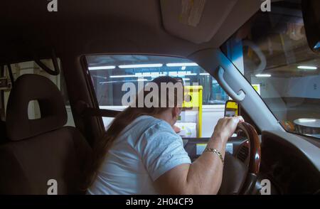 Frau holt ein Ticket an einem Automaten am Eingang eines mehrstöckigen Parkhauses in Venedig, Italien, ab Stockfoto