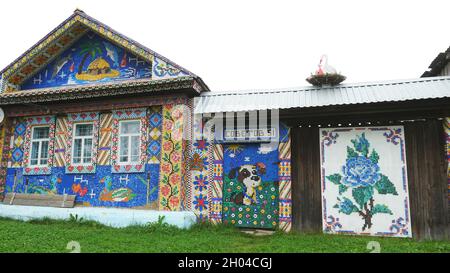 Ungewöhnliche Fassade ein altes Holzhaus mit bunten Mosaikbildern aus kleinen Plastikflaschen-Kappen, Kreativitätskonzept dekoriert. Schöne und helle Hand Stockfoto
