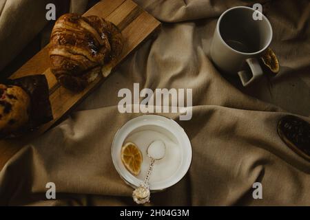 Draufsicht Tasse Kaffee leer, Kaffeebohnen und gemahlen mit Croissant und Muffin. Getränke- und Essenskonzept Frühstück. Stockfoto