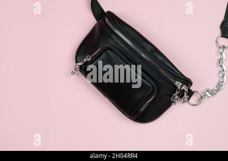 Bananenbeutel. Gürteltasche aus schwarzem Leder auf rosa Hintergrund. Stilvolle Damen-Handtasche. Stockfoto