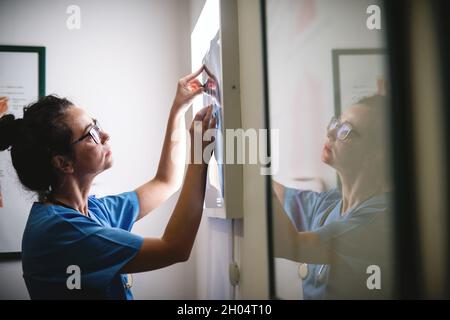 Ärztin, die das Röntgenbild mit ernstem Gesicht betrachtet. Stockfoto