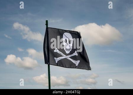 Totenkopf und Kreuzknochen, Piratenflagge vor blauem Himmel. Stockfoto