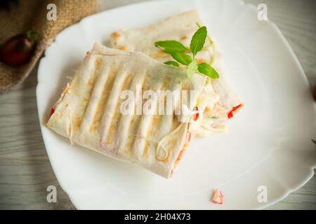 Gebackene Pita-Rolle mit Füllung in einem Teller auf dem Tisch Stockfoto