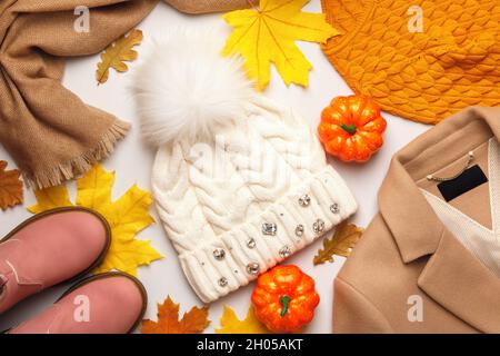 Ein Satz warmer Herbst-Winter-Kleidung mit heruntergefallenen Blättern und Kürbissen auf weißem Hintergrund. Flach liegend, Draufsicht Stockfoto