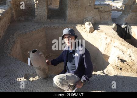 YAVNE, 11. Oktober 2021 (Xinhua) -- der israelische Archäologe und Yavne-Grabungsdirektor Elie Hadad zeigt ein Reliquienstück, das am 11. Oktober 2021 an der Ausgrabungsstätte einer alten Weinfabrik in Yavne in Zentralisraelien gefunden wurde. Israelische Archäologen haben eine 1,500 Jahre alte riesige Weinfabrik aufgedeckt, sagte die israelische Antiquitätenbehörde (IAA) am Montag. Das riesige und gut gestaltete Industriegebiet aus der byzantinischen Zeit wurde in den letzten zwei Jahren in der Stadt Yavne in Zentralisraelien ausgegraben. (Foto von Gil Cohen Magen/Xinhua) Stockfoto