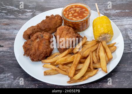 Gebratenes Huhn mit Pommes Frites, gebackene Bohnen und Süßmais Abendessen Stockfoto