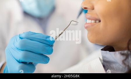 Nicht Erkennbarer Zahnarzt In Blauem Sterilen Handschuh Mit Zahnsondenwerkzeug, Bereit Für Die Überprüfung Mit Lächelnder Weiblicher Patientin, Nahaufnahme Der Stomatologin Stockfoto