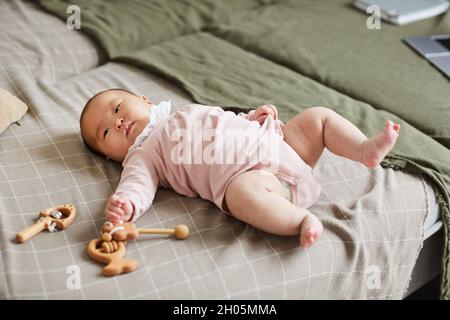 Bild von niedlichen Mädchen auf dem Bett im Schlafzimmer liegen und spielen mit ihren Spielsachen Stockfoto