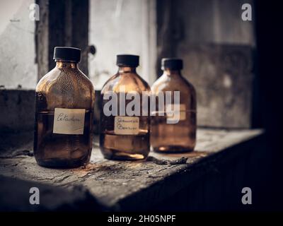 Nahaufnahme von drei Flaschen mit Flüssigkeit auf einem alten beschädigten Balkon. Stockfoto