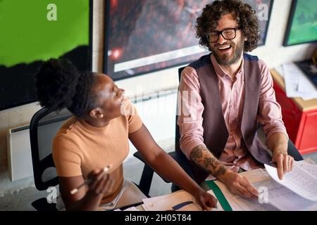 Junge, enthusiastische Mitarbeiter machen gemeinsam im Büro Schreibarbeiten Stockfoto