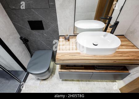 Modernes, minimalistisches, helles Badezimmer mit weißem Waschbecken und Holzmöbeln. Interior Design Konzept Stockfoto