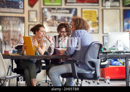 kaukasische Gruppe von Kollegen, die zusammen arbeiten, lächeln, lachen, Spaß an der Arbeit haben. Stockfoto
