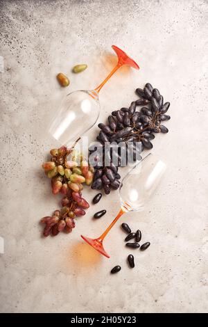 Weinflaschen mit Weintrauben und Weinläsern auf altem grauen Beton-Tischhintergrund mit Kopierraum. Rotwein mit Weinrebe. Weinkomposition auf Rusti Stockfoto