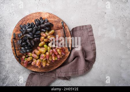 Weinflaschen mit Weintrauben und Weinläsern auf altem grauen Beton-Tischhintergrund mit Kopierraum. Rotwein mit Weinrebe. Weinkomposition auf Rusti Stockfoto