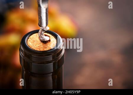 Flasche Wein mit Korkenzieher. Öffnen einer Weinflasche mit Korkenzieher in einem Restaurant. Weinkomposition auf dunklem rustikalem Hintergrund mit Kopierfläche. Mock U Stockfoto