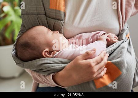 Nahaufnahme eines niedlichen Mädchens, das schläft, während ihre Mutter sie an den Händen hält Stockfoto