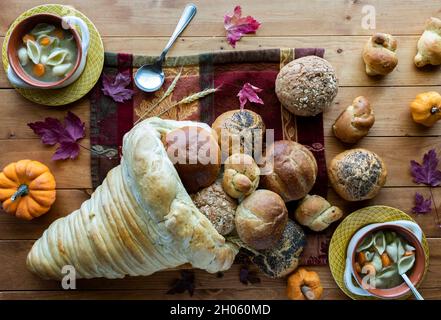 Ein Brotcornucopia mit ausströmenden Brötchen und zwei Schüsseln putensuppe. Stockfoto