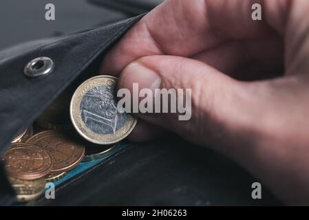 Nahaufnahme einer Person, die 1 Euro-Münze aus der Brieftasche nimmt, Taschengeld-Geschäftskonzept Stockfoto