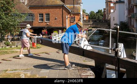 Newbury, Bekshire, England, Großbritannien. 2021. Das Paar wartet darauf, dass sich das Schloss füllt und blickt auf die alte Stadtbrücke und eine Kneipe mit Blumenschmuck neben dem Ken Stockfoto