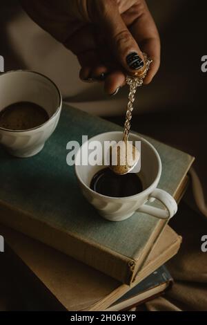 Zwei Kaffeetassen mit einem Original-Löffel auf Büchern auf einem isolierten beigen Hintergrund. Stockfoto