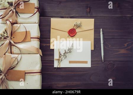 Oben von Handwerk Geschenkbox und Grußkarte mit Stift auf Holztisch Hintergrund Stockfoto