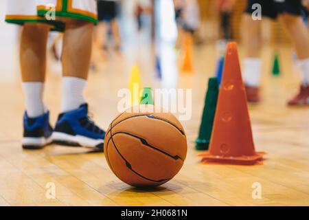 Kinder üben Basketball auf dem Schulhof. Basketball Training Game Hintergrund. Basketball- und Trainingskegel auf Holzboden Nahaufnahme mit Blurr Stockfoto