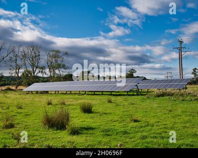 Große Sonnenkollektoren in Ackerland im Nordosten Englands. Aufgenommen an einem sonnigen Herbsttag mit blauem Himmel und leichten Wolken. Stockfoto