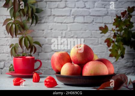 Reife rote Äpfel auf einem Küchentisch vor Backsteinwänden Stockfoto