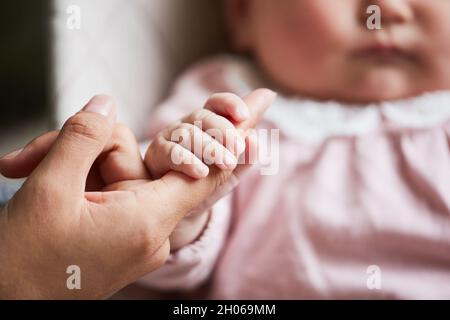 Nahaufnahme eines Neugeborenen, das die Hand seiner Mutter hält Stockfoto