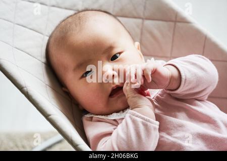 Nahaufnahme von asiatischen niedlichen Baby-Mädchen Blick auf die Kamera, während sie sich auf dem Bett Stockfoto