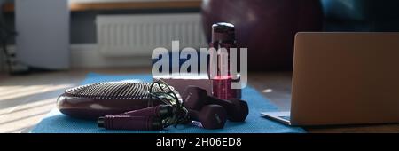Kurzhantel Balancierkissen und Sportgeräte auf Sportmatte mit Laptop Stockfoto