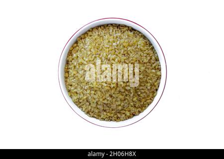 Bulgurkörner. Draufsicht auf rohe Bulgur-Körner in der Schüssel auf isoliertem weißem Hintergrund. Stockfoto