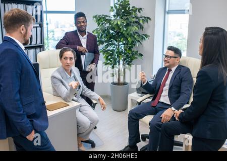 Gruppe interkultureller Kollegen, die im Büro über neue Ideen diskutieren Stockfoto