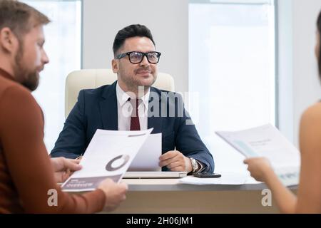 Seriöser Anwalt oder Wirtschaftsprüfer hört jungen Frauen zu, während er seine Klienten im Büro berät Stockfoto