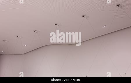 Abgehängte Decke mit Kurven und hängenden Blitzen im Bürogebäude Stockfoto