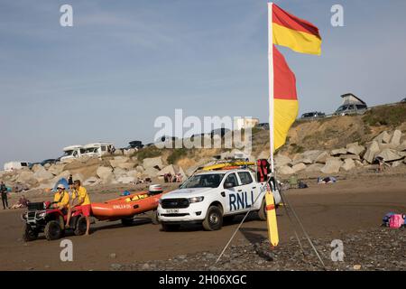 RNLI Rettungsschwimmer mit Fahrzeugen, Quad und aufblasbarem Lifer im Einsatz am Widemouth Surfing Beach Devon UK Stockfoto