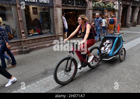 Frau Reiten Fahrrad Schleppen Kinder cbike Anhänger Elsass, Frankreich Stockfoto