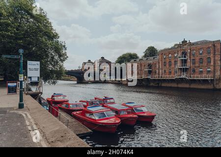 York, Großbritannien - 22. Juni 2021: Selbstfahrende rote Mietboote, die an einem Fluss Ouse in York festgemacht sind. Mieten Sie Boote, um die von Th gegründete Stadt zu erkunden Stockfoto