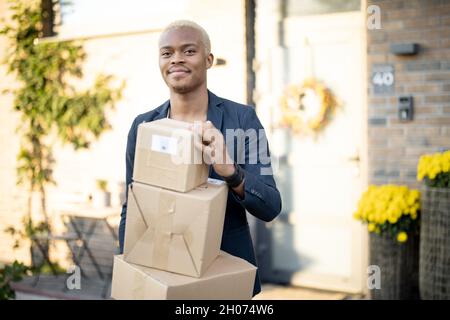 Lateinischer Mann, der mit Paketen in der Nähe seines Hauses steht Stockfoto
