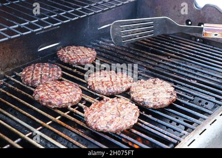 Hamburgers auf einem Grill im Freien drehen Stockfoto