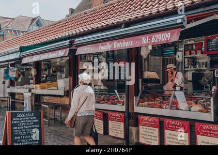 York, Großbritannien - 22. Juni 2021: Swain Family Butchers Marktstand im Shambles Market, einem täglichen Markt im Stadtzentrum von York, bei dem Frauen zu Fuß unterwegs sind Stockfoto