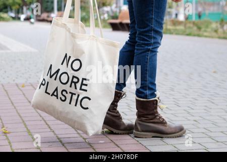 Menschliche Füße in Jeans und Stiefeln mit einer Tasche mit der Aufschrift kein Plastik mehr Stockfoto