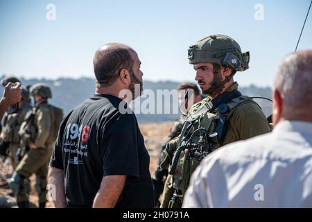 Israel Defence forces Soldaten verhindern den Zugang von Einheimischen und Aktivisten von Olivenplantagen während der Erntezeit. Die Plantage am Stadtrand von Salfit wurde im letzten Jahr an einen neuen jüdischen Vorposten angeschlossen - „AVI view Farm“, obwohl die Plestinier Landtaten für das Land besitzen. Während eines Versuchs, die weiße Linie zu durchbrechen, die eine geschlossene Militärzone in den Plantagen einschließt, verwendete die Armee Betäubungsgranaten und verhaftete drei Aktivisten. Salfit, das Westjordanland, am 11. Oktober 2021. (Matan Golan/Alamy Live News) Stockfoto