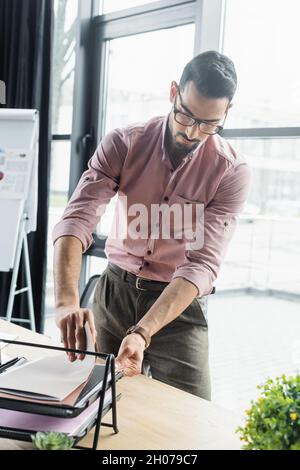 Arabischer Geschäftsmann sucht im Büro nach Papieren Stockfoto