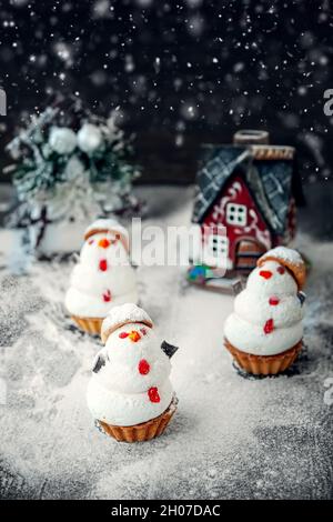 Schneemann aus süßem Meringue mit weihnachtlichen Dekorationen. Original-Marschlallchen und Baiser-Kekse auf dem Weihnachtstisch. Cookies in Form eines Stockfoto