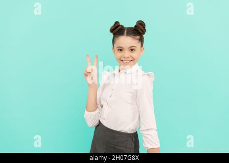 Friedensstifter. Kinder im Schulalter zeigen V-Schild. Happy Kid blauen Hintergrund. Grundbildung. Zurück zur Schule Stockfoto