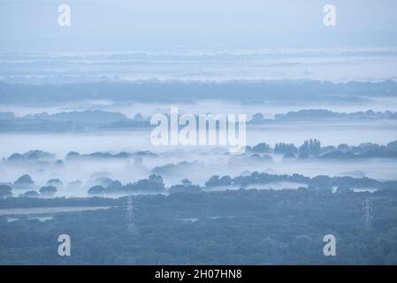 Atemberaubendes nebliges Landschaftsbild am Morgen, das im Spätsommer über Felder im South Downs National Park im rollenden englischen Gegenbild blickt Stockfoto