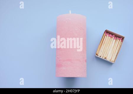 Streichhölzer in einer offenen Schachtel auf der hellrosa Kerze auf dem blauen Tisch Stockfoto