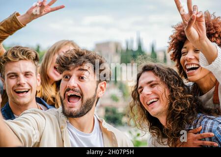 Freunde Studenten entspannen sich draußen, machen Gruppen Selfies und lächeln auf dem Smartphone, auf der Straße Stockfoto