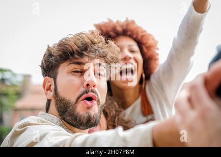 Freunde Studenten entspannen sich draußen, machen Gruppen Selfies und lächeln auf dem Smartphone, auf der Straße Stockfoto